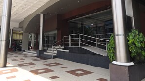 Une entrée moderne, avec un sol carrelé, des colonnes en métal et un escalier menant à un niveau supérieur.