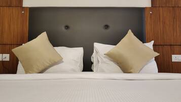 A neatly made bed with white linens and two beige pillows, set against a dark headboard with wooden paneling on the sides.