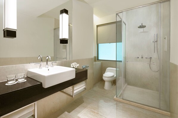 A modern bathroom with a glass-enclosed shower, a white sink, and a large mirror.
