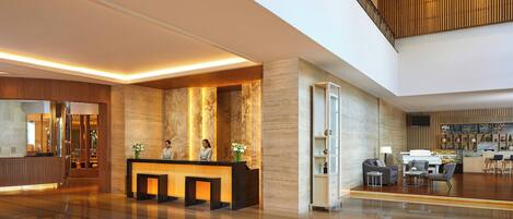 A spacious lobby with a reception desk, seating area, and a staircase leading to an upper level.