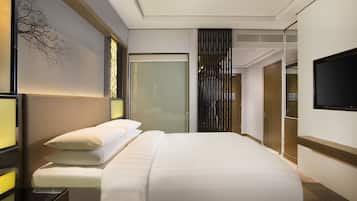 Una habitación de hotel moderna con una cama grande, una mesita de noche, un televisor de pantalla plana en la pared y una puerta corredera que da a un baño.