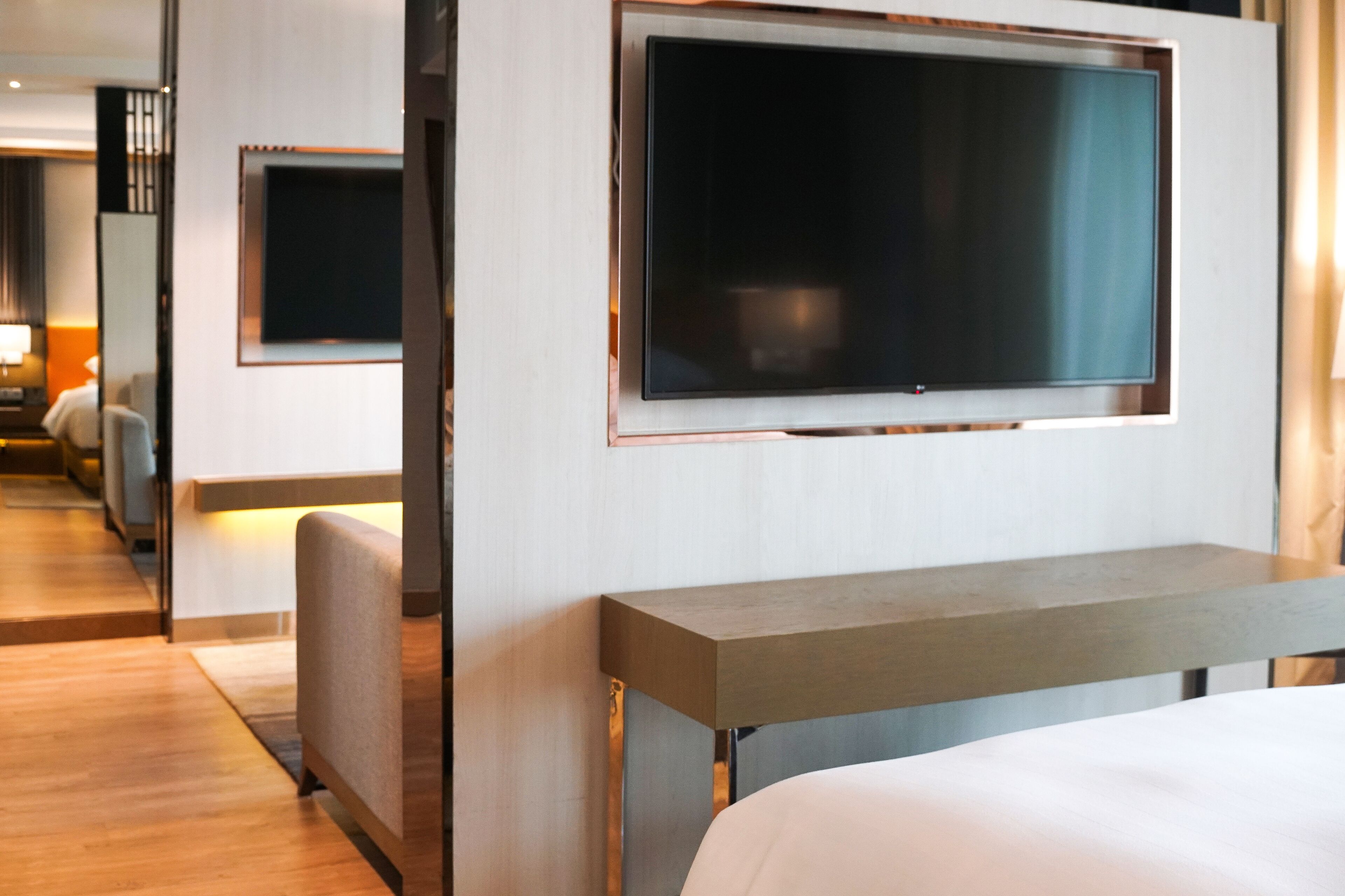 Una camera d'hotel moderna con un letto grande, una TV a schermo piatto montata a parete, un piccolo angolo salotto e pavimento in legno.