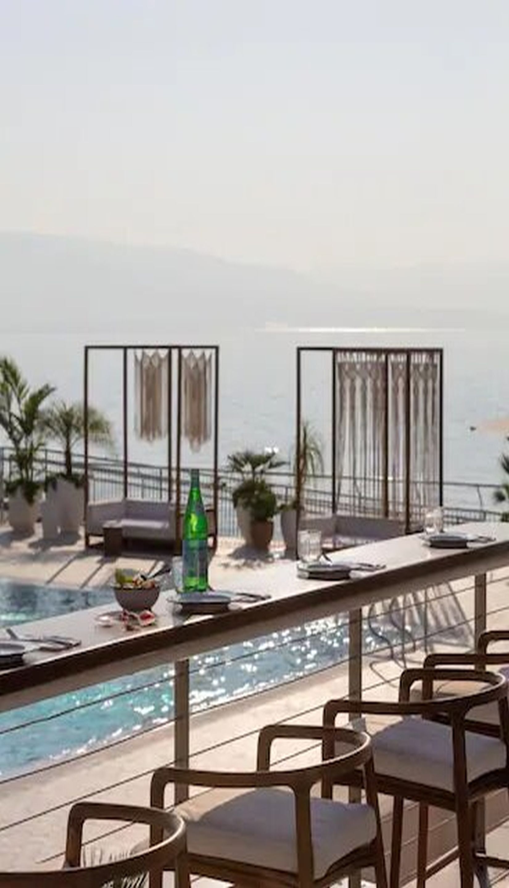 Un balcón con piscina, sillas y vistas al mar.