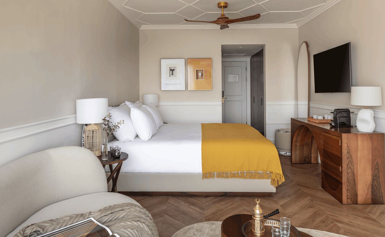 Una habitación de hotel con una cama, un escritorio, un televisor y un ventilador de techo.