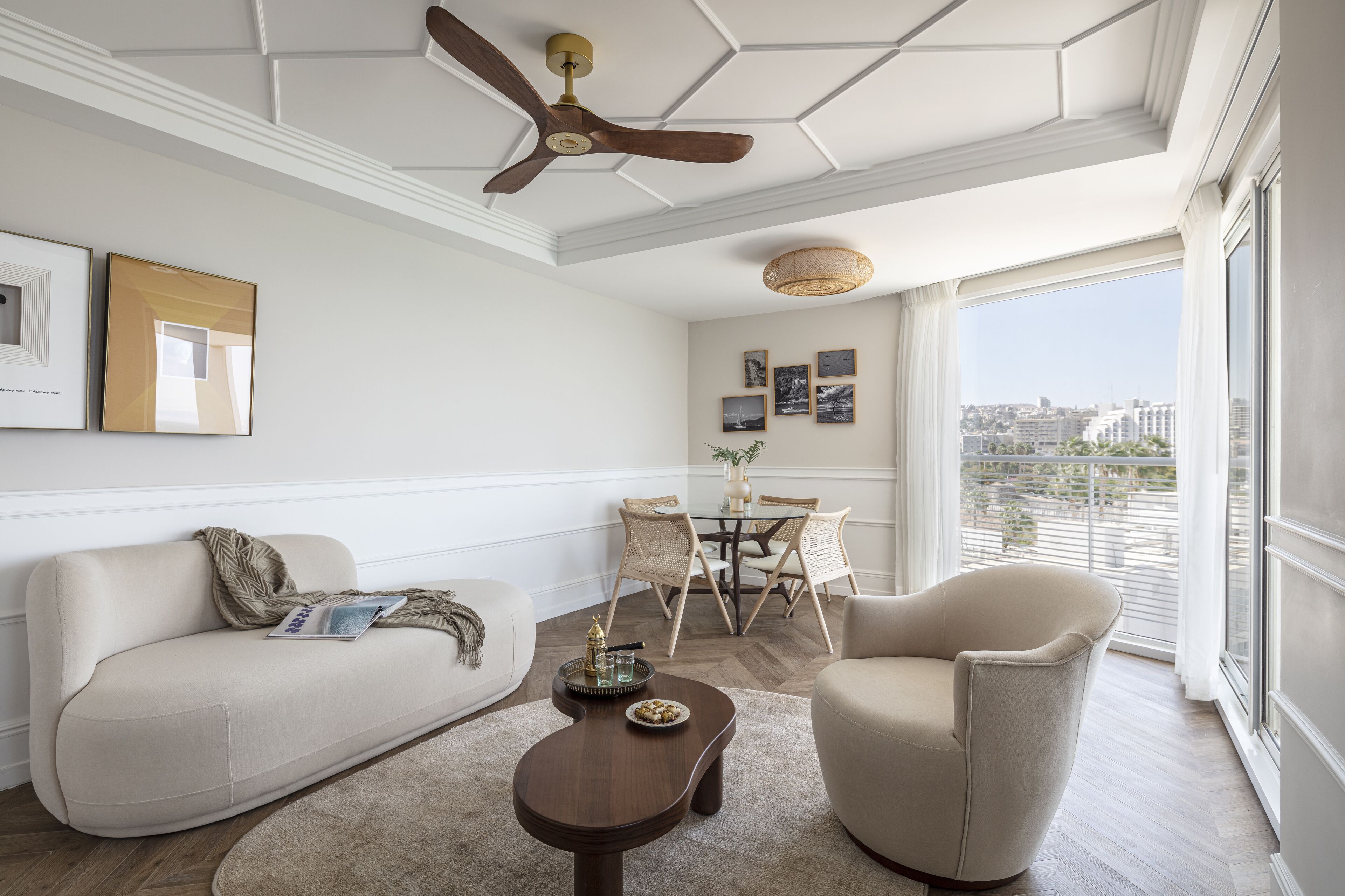 A modern living room with a sofa, armchair, coffee table, and dining area with chairs and a table.