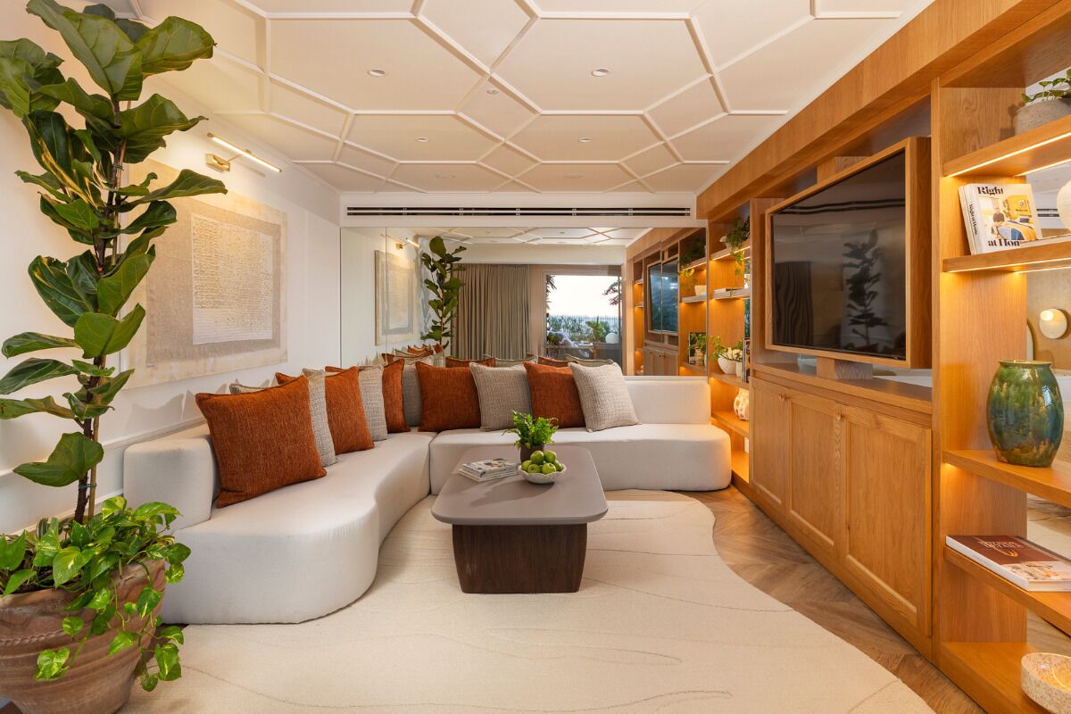Un salon moderne avec un canapé d’angle, une table basse et un meuble en bois sur lequel est posée une télévision.