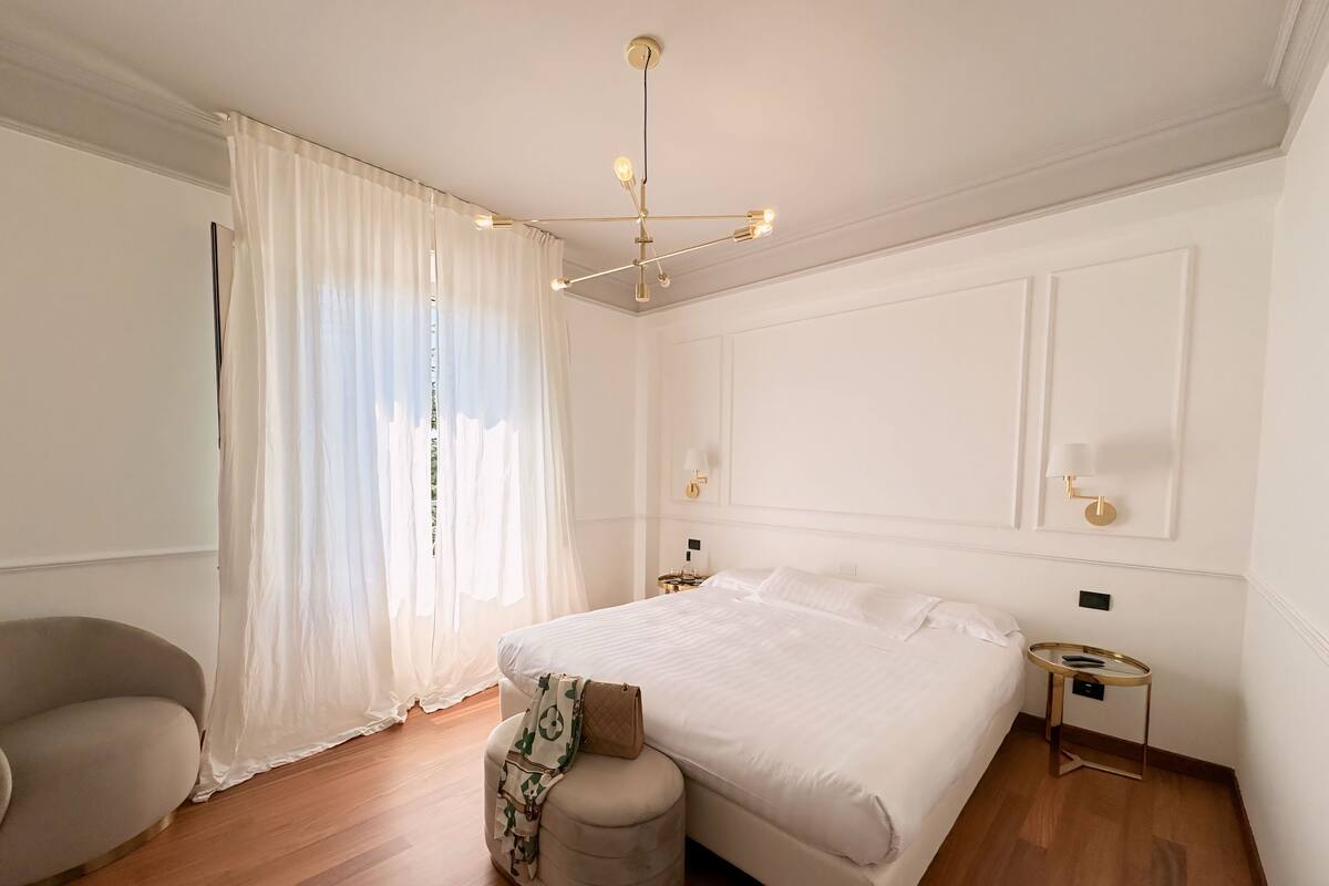 A modern bedroom with a large bed, a bedside table, a lamp, and a chair.