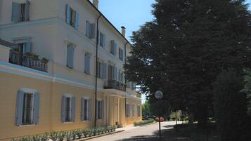 A multi-story building with balconies, a paved street, and trees.