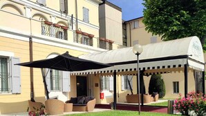 A building with a covered outdoor seating area, a garden with pink roses, and a sign that reads "Ristorante". - Rechigi Park Hotel (Modena)