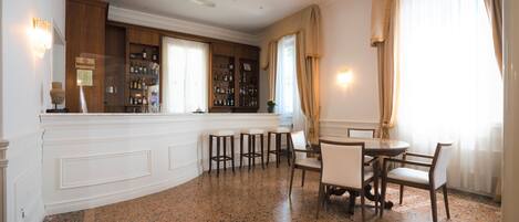 Una zona de bar con una barra curva, taburetes y una mesa de comedor con sillas.