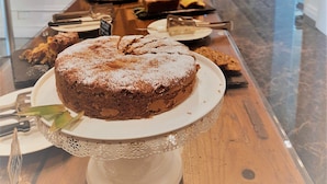 A dessert buffet with a variety of cakes and pastries on a wooden table, set against a modern interior with a large abstract painting on the wall. - Rechigi Park Hotel (Modena)