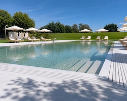 Una piscina al aire libre de temporada, sillones reclinables de piscina