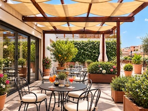 An outdoor patio area with round tables and chairs, surrounded by potted plants and a wooden pergola. - Hotel Dei Mellini (Rome)