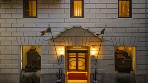 Fachada de hotel con un diseño simétrico, que presenta una entrada central con puertas dobles y un pequeño balcón.