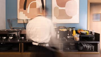 Una cocina con mostrador, diferentes electrodomésticos y una exhibición de frutas y condimentos.