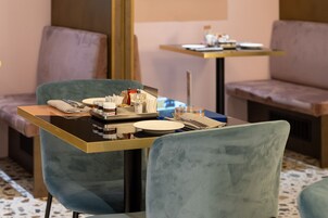 A dining area with a table set for two, featuring a tray with condiments, a plate, and cutlery.