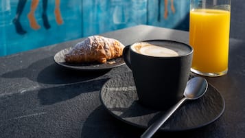 Una mesa con un croissant, una taza de café y un vaso de jugo de naranja.