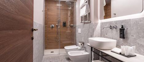 Un baño moderno con ducha acristalada, un lavamanos amplio y un inodoro.