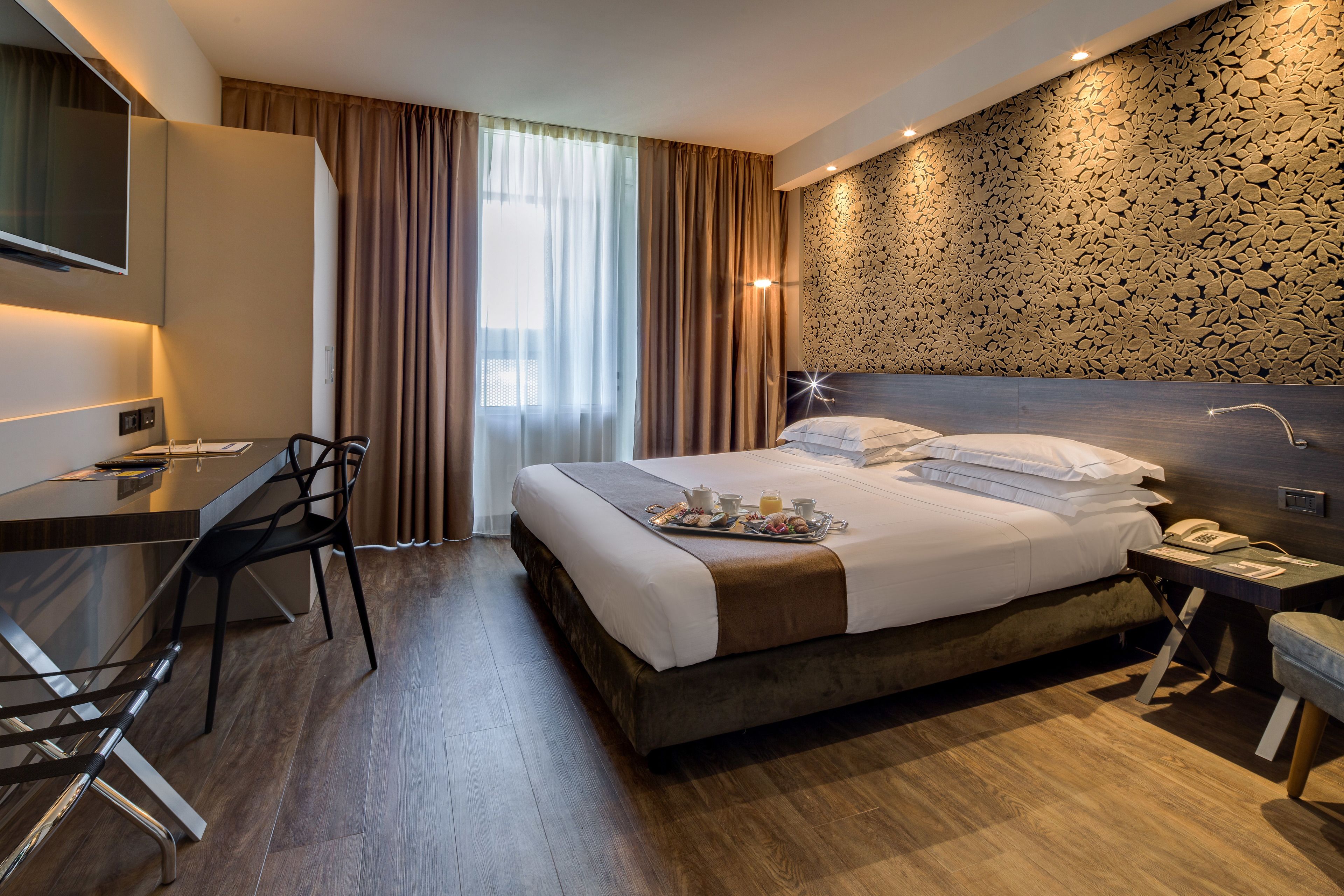 Een moderne hotelkamer met een groot bed, een bureau met stoel, een televisie en een badkamer met douche.