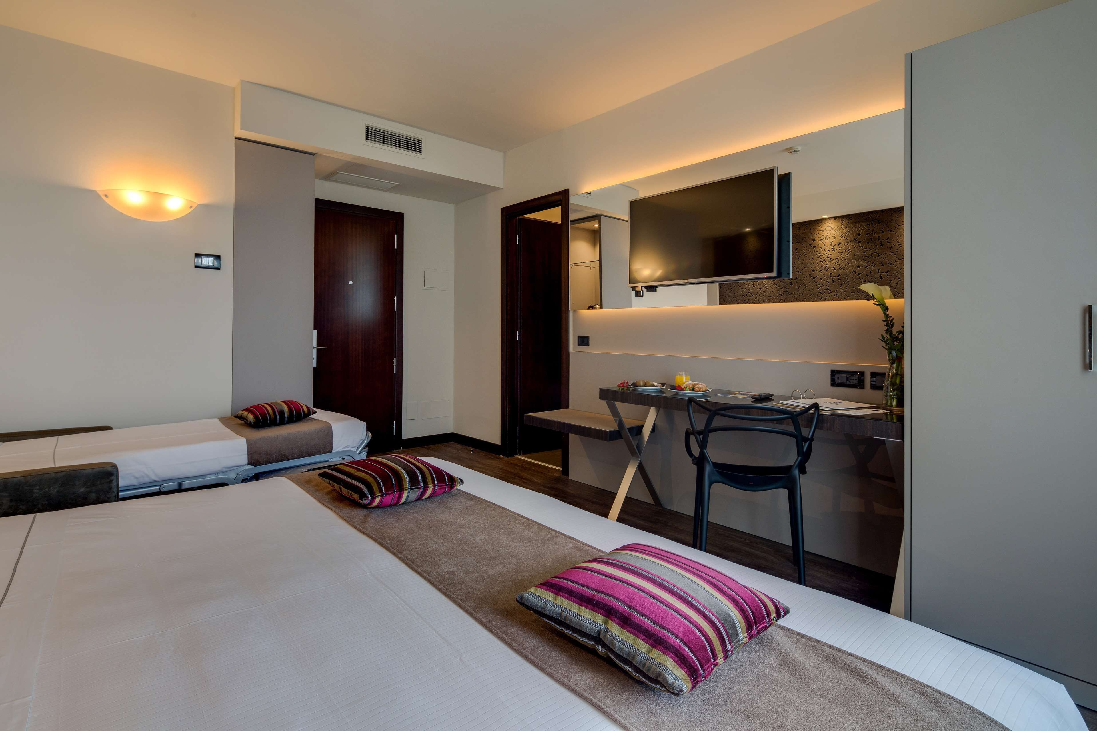 Une chambre d’hôtel avec un lit, un bureau, une chaise et un téléviseur.