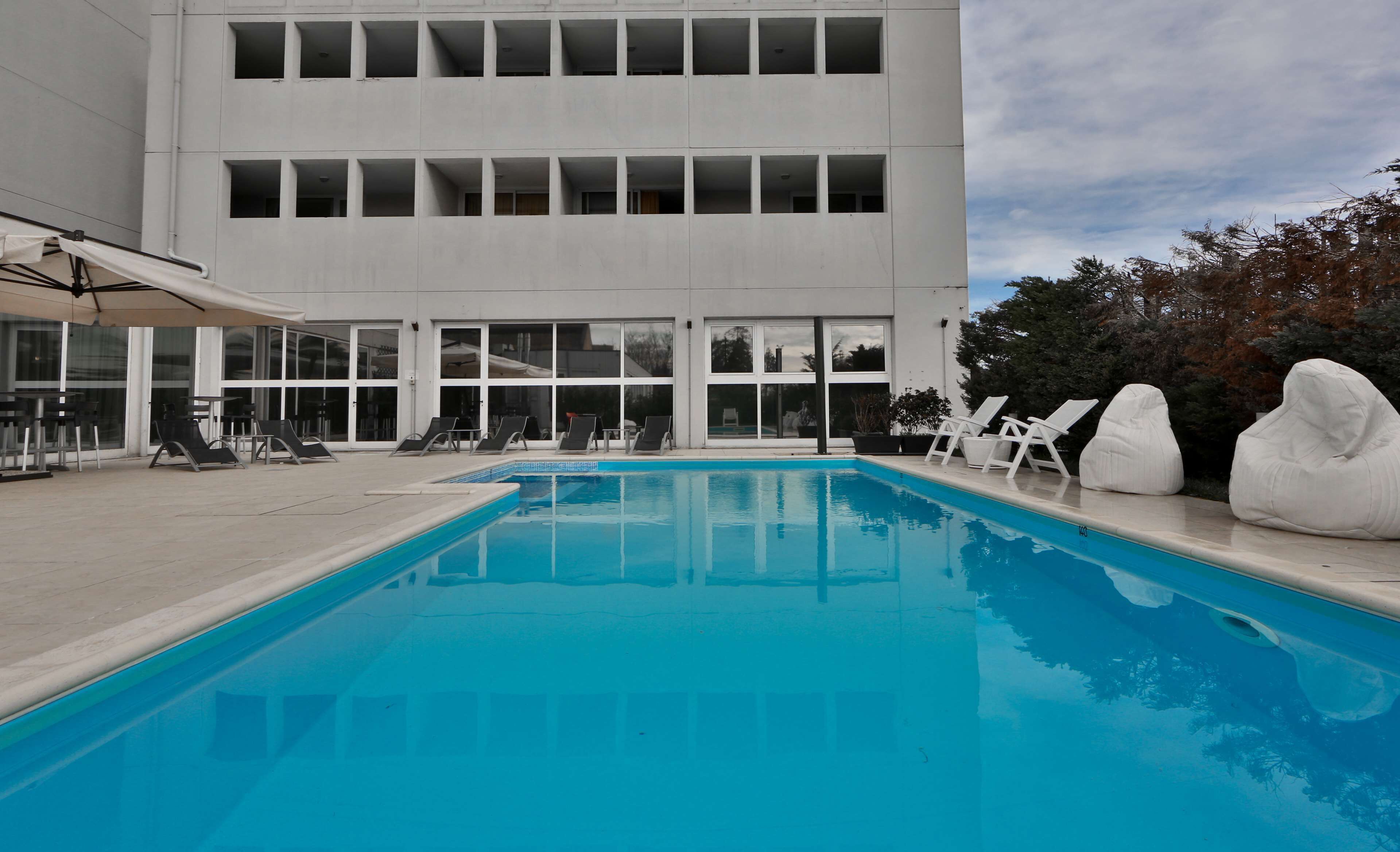 A swimming pool with lounge chairs and a building with multiple windows in the background.