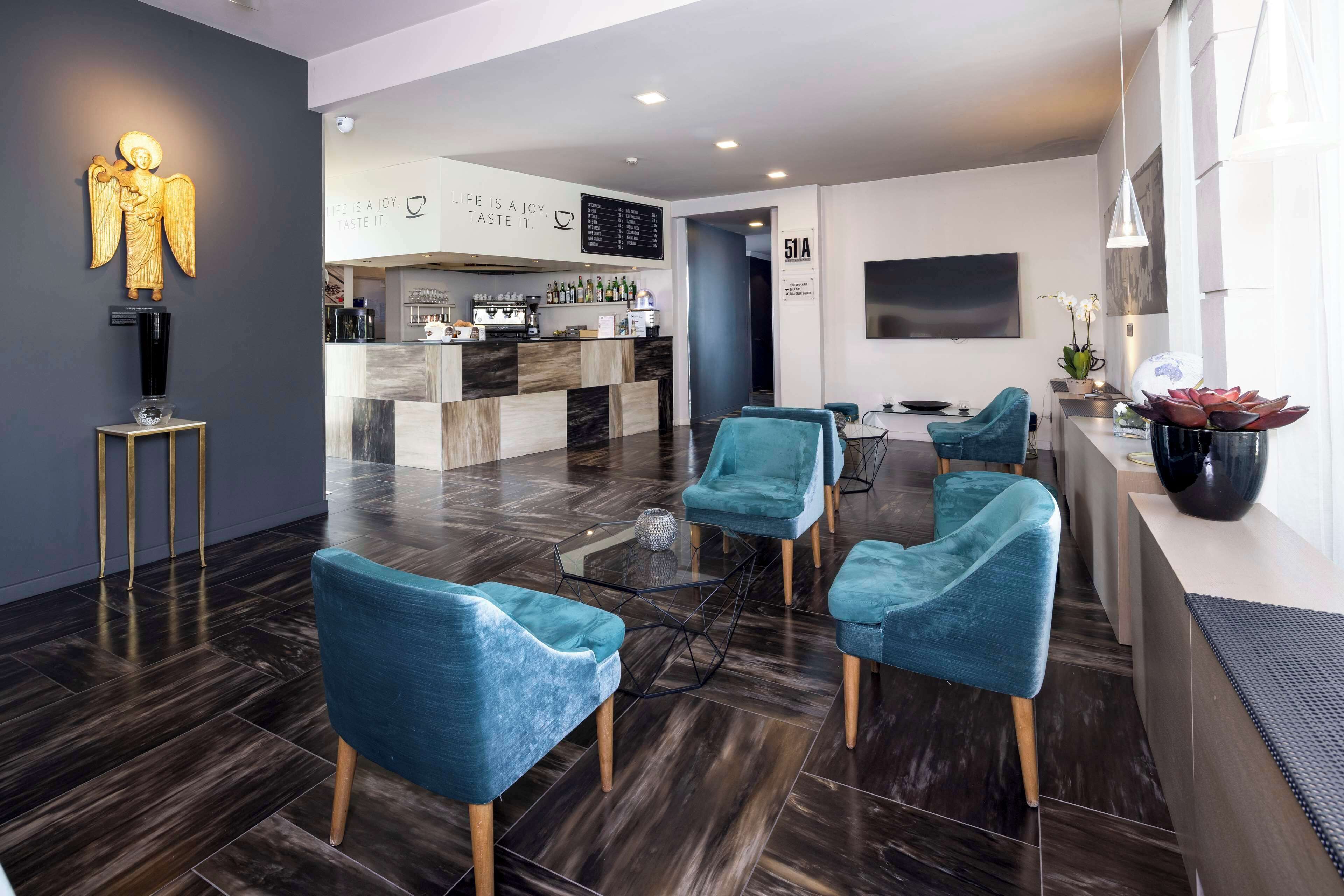 A modern interior with teal chairs, a bar area, and a large screen.