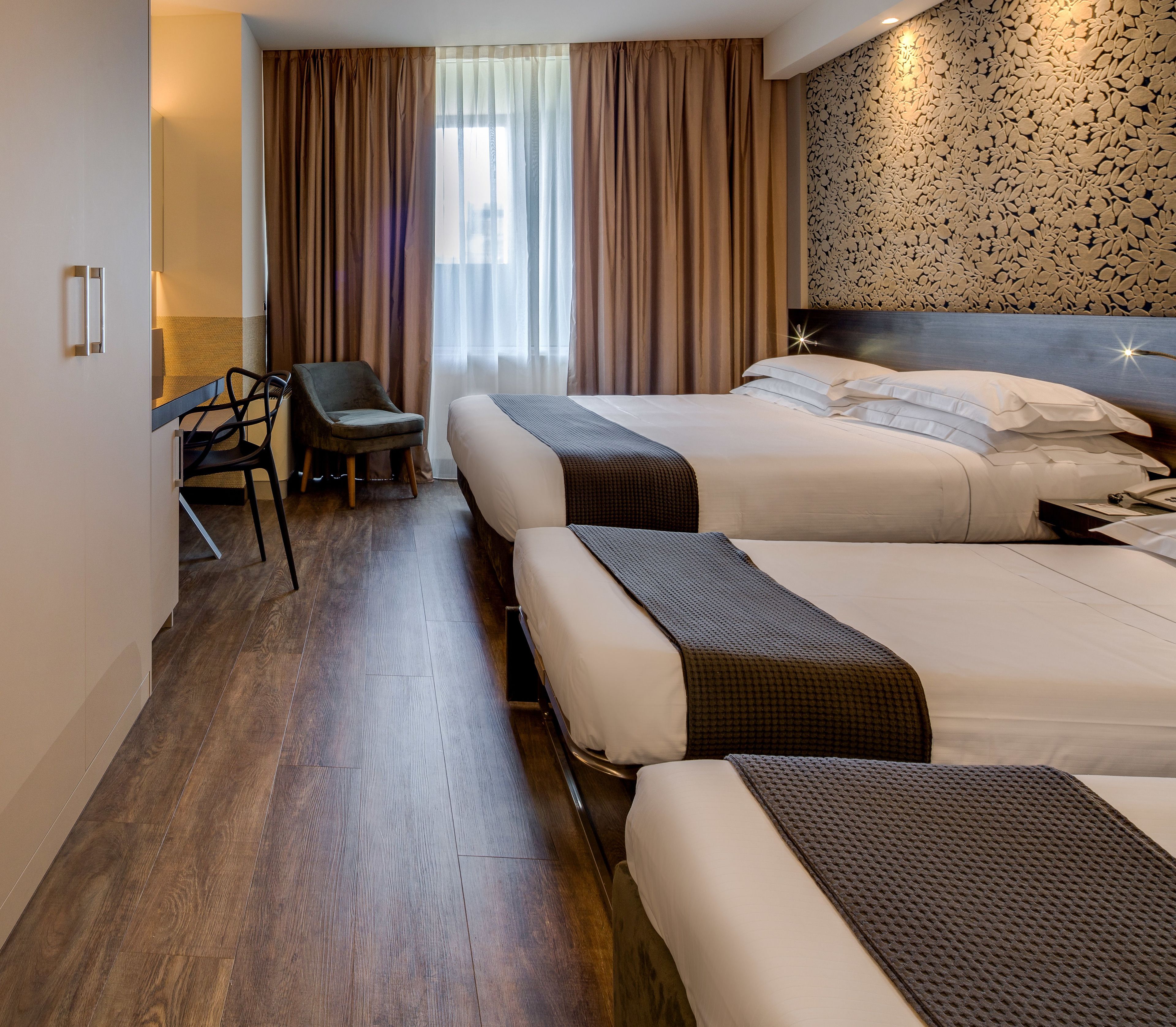 A hotel room with two beds, a desk, and a chair.