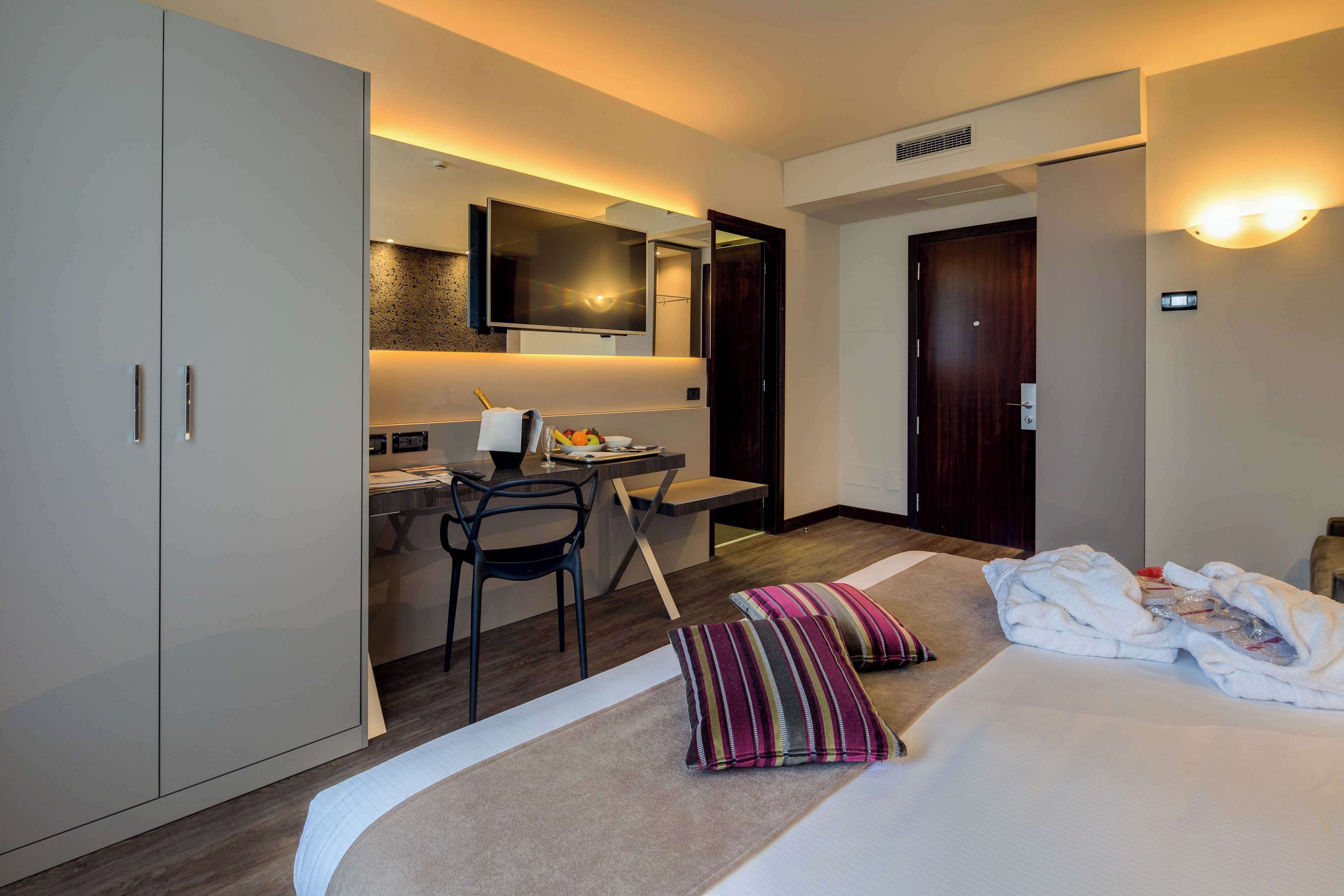 Una habitación de hotel con una cama, un escritorio, una silla, un televisor y un armario.