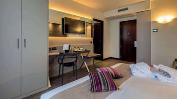 Una habitación de hotel con una cama, un escritorio, una silla, un televisor y un armario.