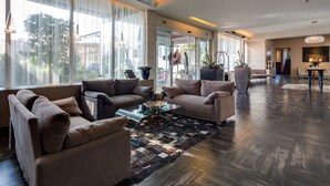 A spacious living area with a large window, a coffee table, and two sofas. - Best Western Plus Hotel Farnese (Parma)