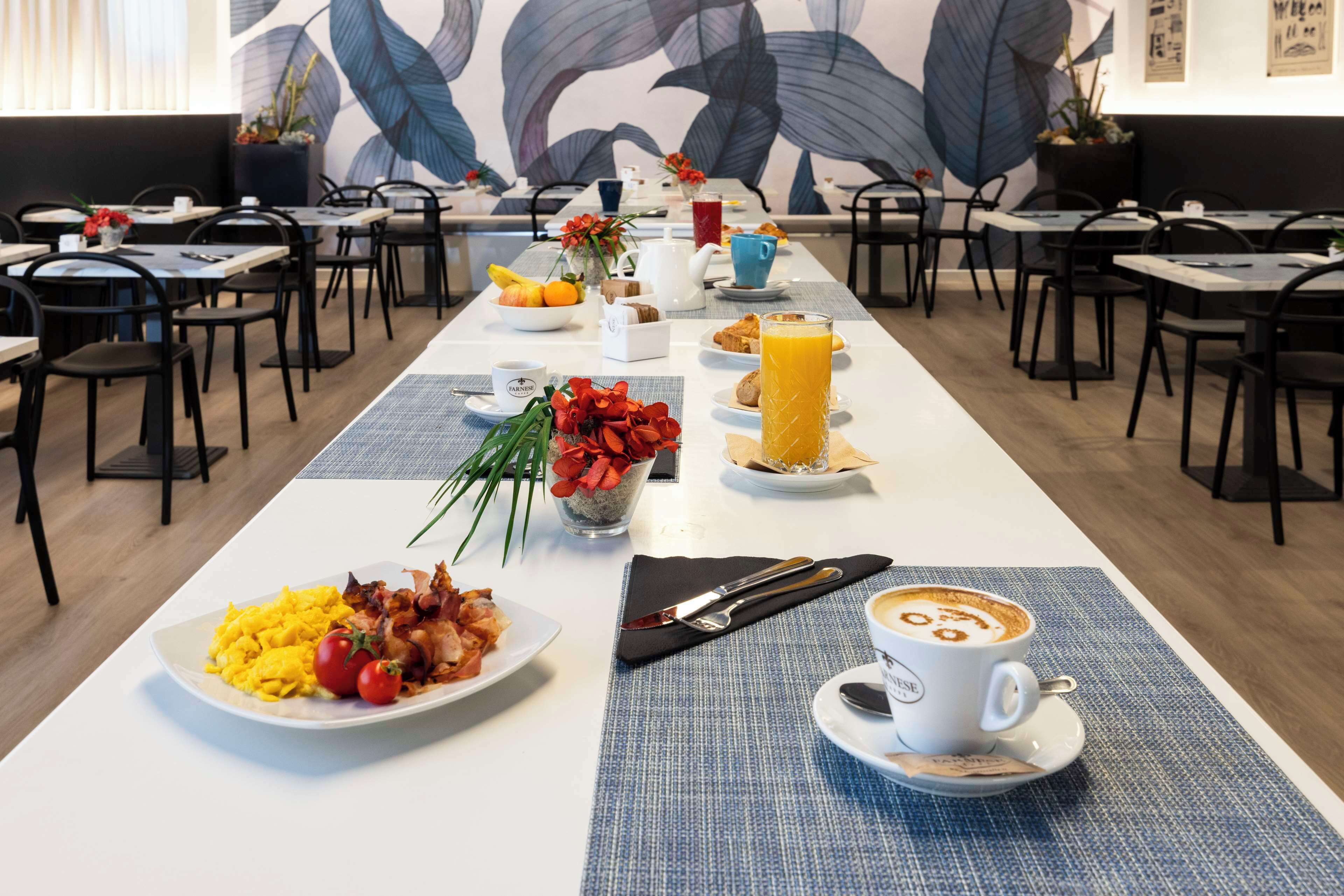 Un desayuno con platos de huevos, tocino y tomates, un vaso de zumo de naranja y una taza de café.