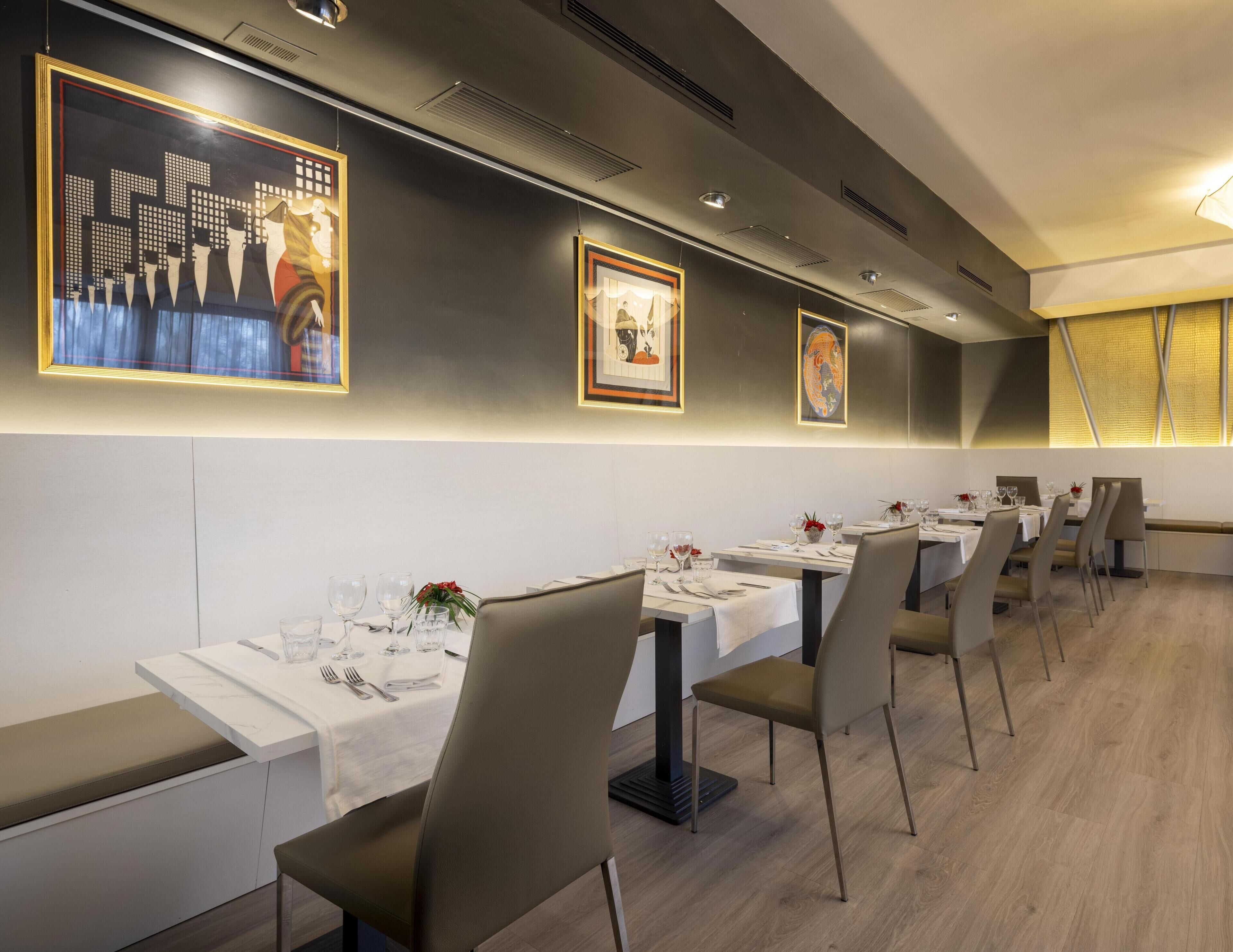 A restaurant with long tables, chairs, and framed artwork on the walls.