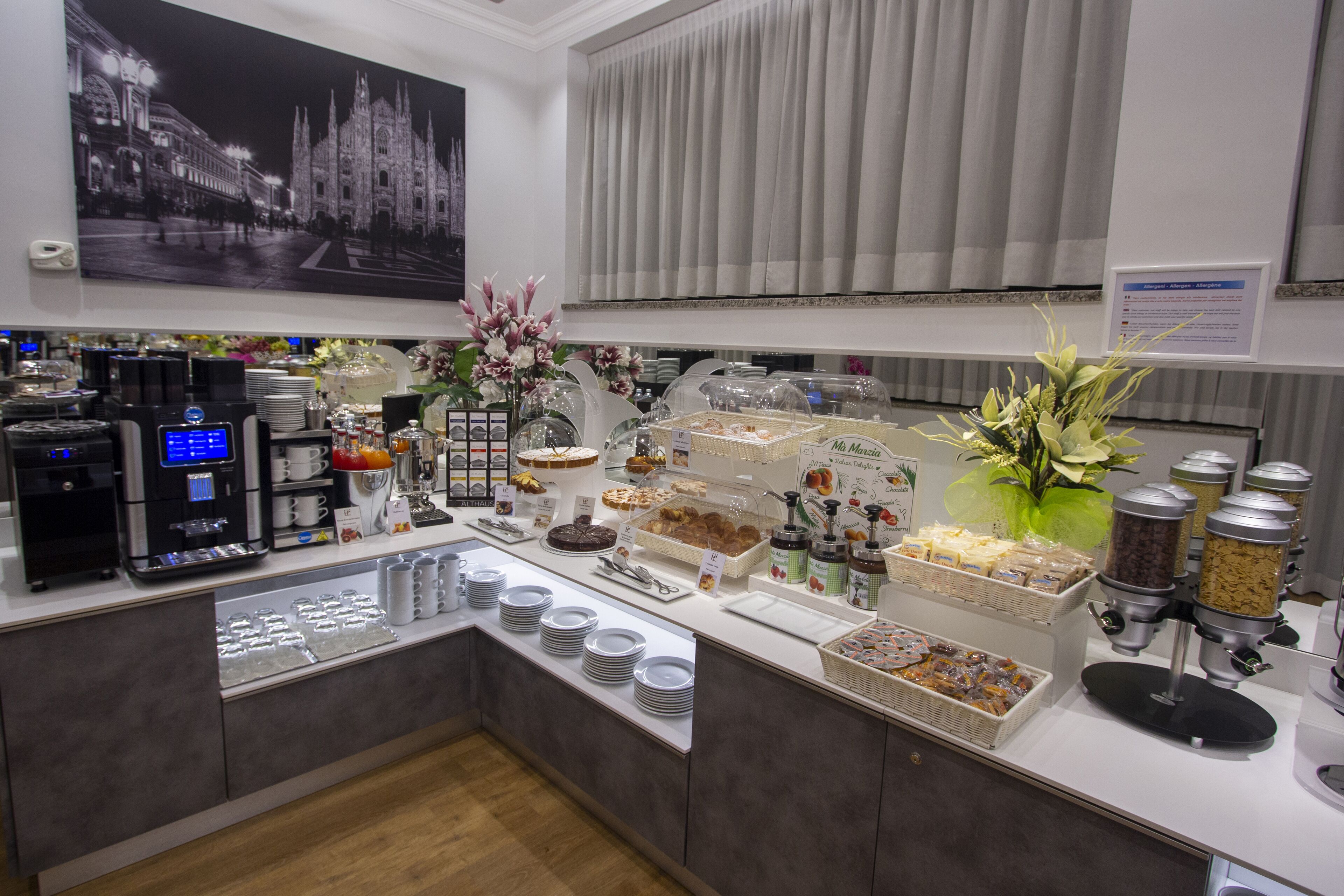 Ein reichhaltiges Frühstücksbuffet mit verschiedenen Speisen, Kaffeeautomaten und dekorativen Blumen.