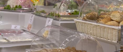 A buffet with various food items, including sandwiches, salads, and bread, displayed in clear containers.