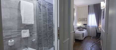 Et moderne badeværelse med en glas brusekabine, et bidet og en håndklæderække.