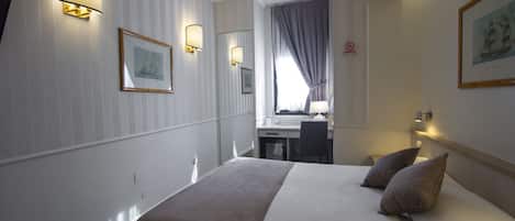 Et hotelværelse med seng, sengeborde, skrivebord og stol.
