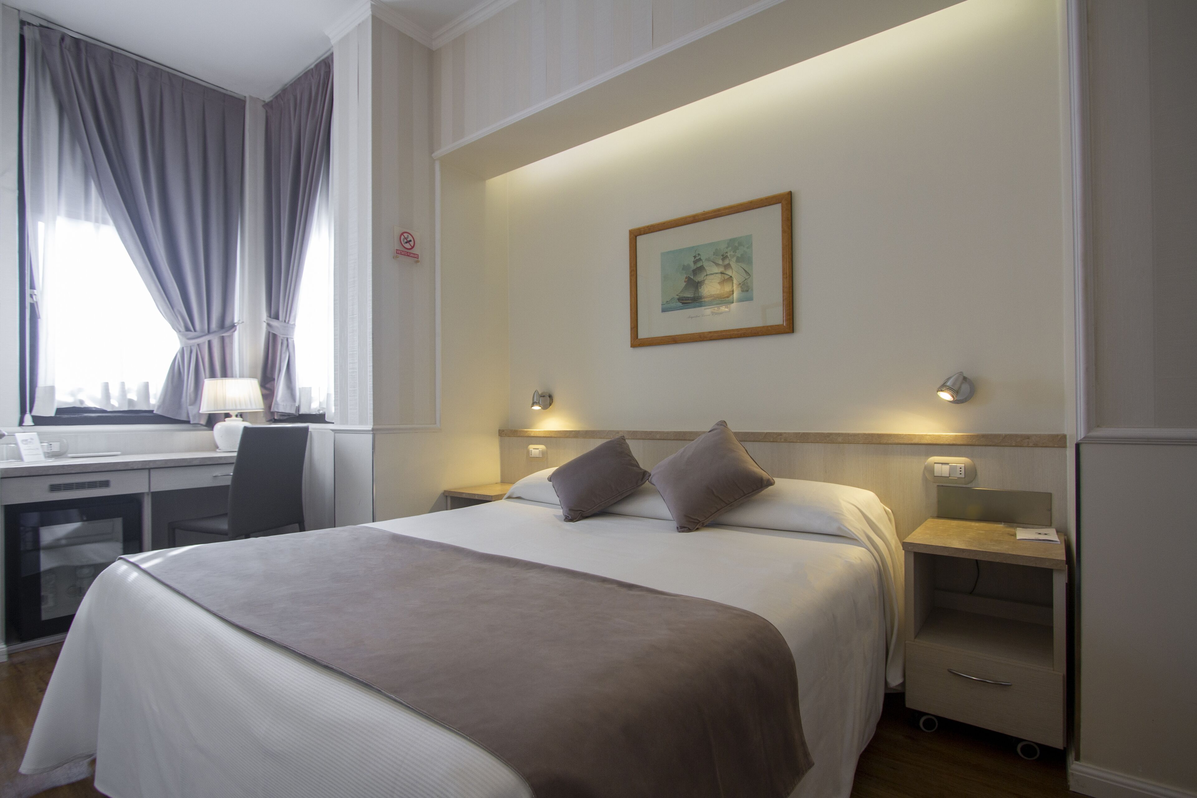 Une chambre d’hôtel avec un lit, des tables de chevet, un bureau et une chaise.