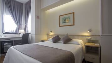 Une chambre d’hôtel avec un lit, des tables de chevet, un bureau et une chaise.