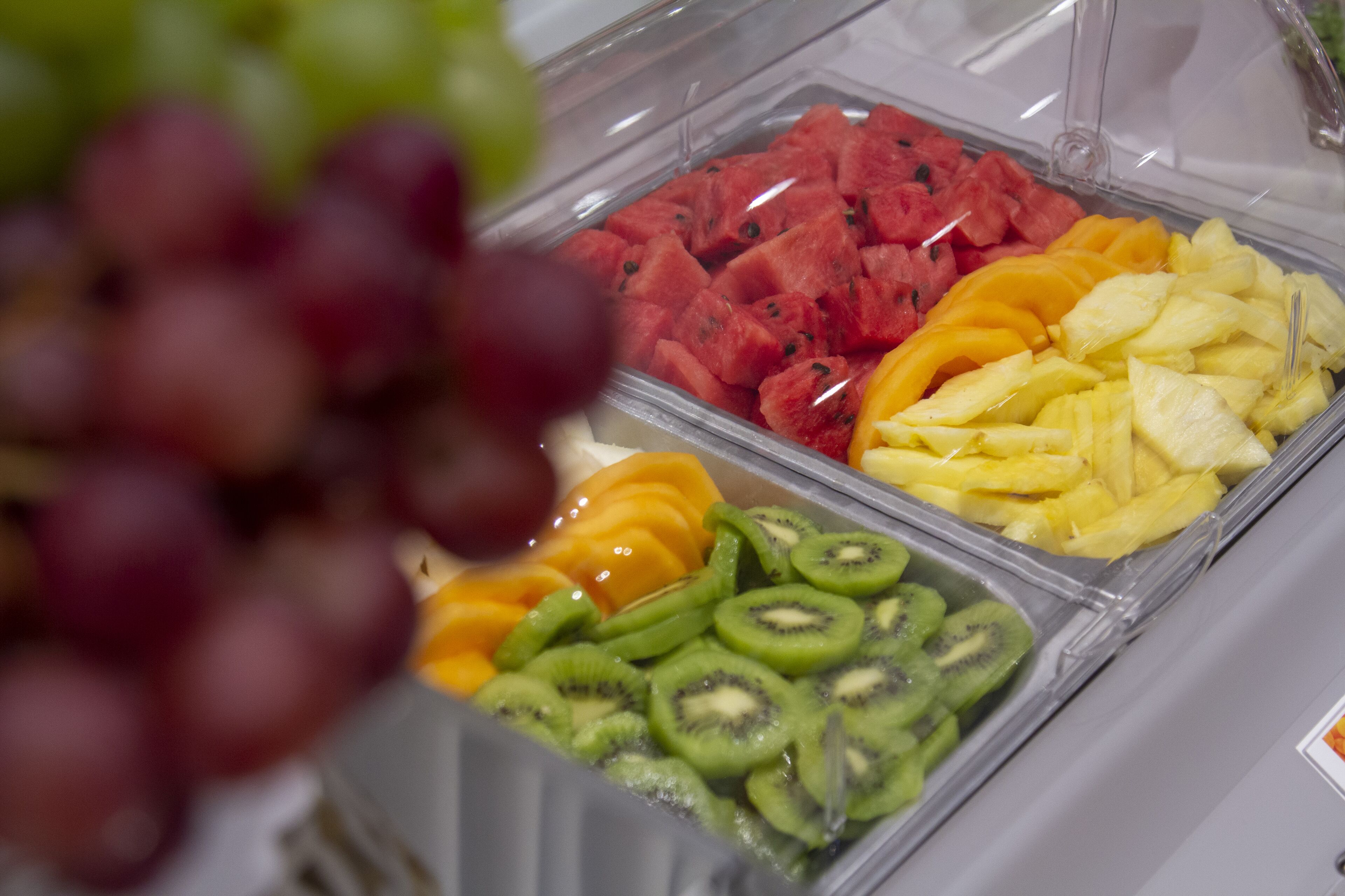 A fruit display with sections for watermelon, mangoes, pineapple, and kiwi.