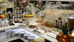 Un buffet proposant une variété de plats, notamment des gâteaux, des pâtisseries et des fruits.