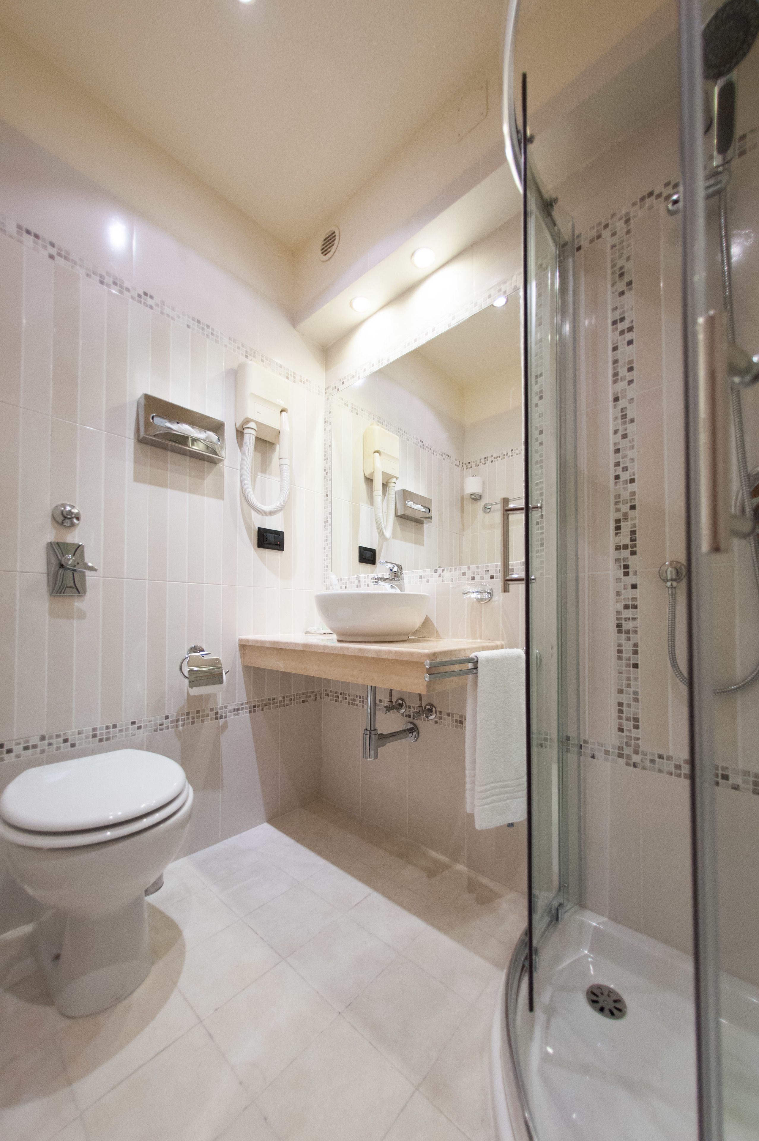 Une salle de bain moderne avec une douche à parois de verre, des toilettes blanches et un lavabo avec un miroir au-dessus.