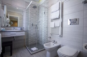Un baño moderno con ducha envuelta en vidrio, un bidé y un inodoro.