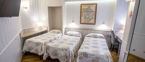 A hotel room with two single beds, a desk, a chair, a TV, and a framed map on the wall.