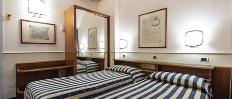 Ein Hotelzimmer mit zwei Betten, einem großen Spiegel und gerahmten Bildern an den Wänden.