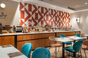 Un bancone di pasticceria con diversi prodotti da forno e una zona con posti a sedere con sedie color acquamarina.