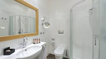 A modern bathroom with a white sink, mirror, and glass shower enclosure.