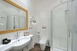 A modern bathroom with a white sink, mirror, and glass shower enclosure.