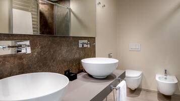 Une salle de bain moderne avec deux grands lavabos blancs, des toilettes et un bidet.