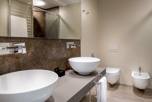 Un baño moderno con dos lavamanos grandes blancos, un inodoro y un bidé.