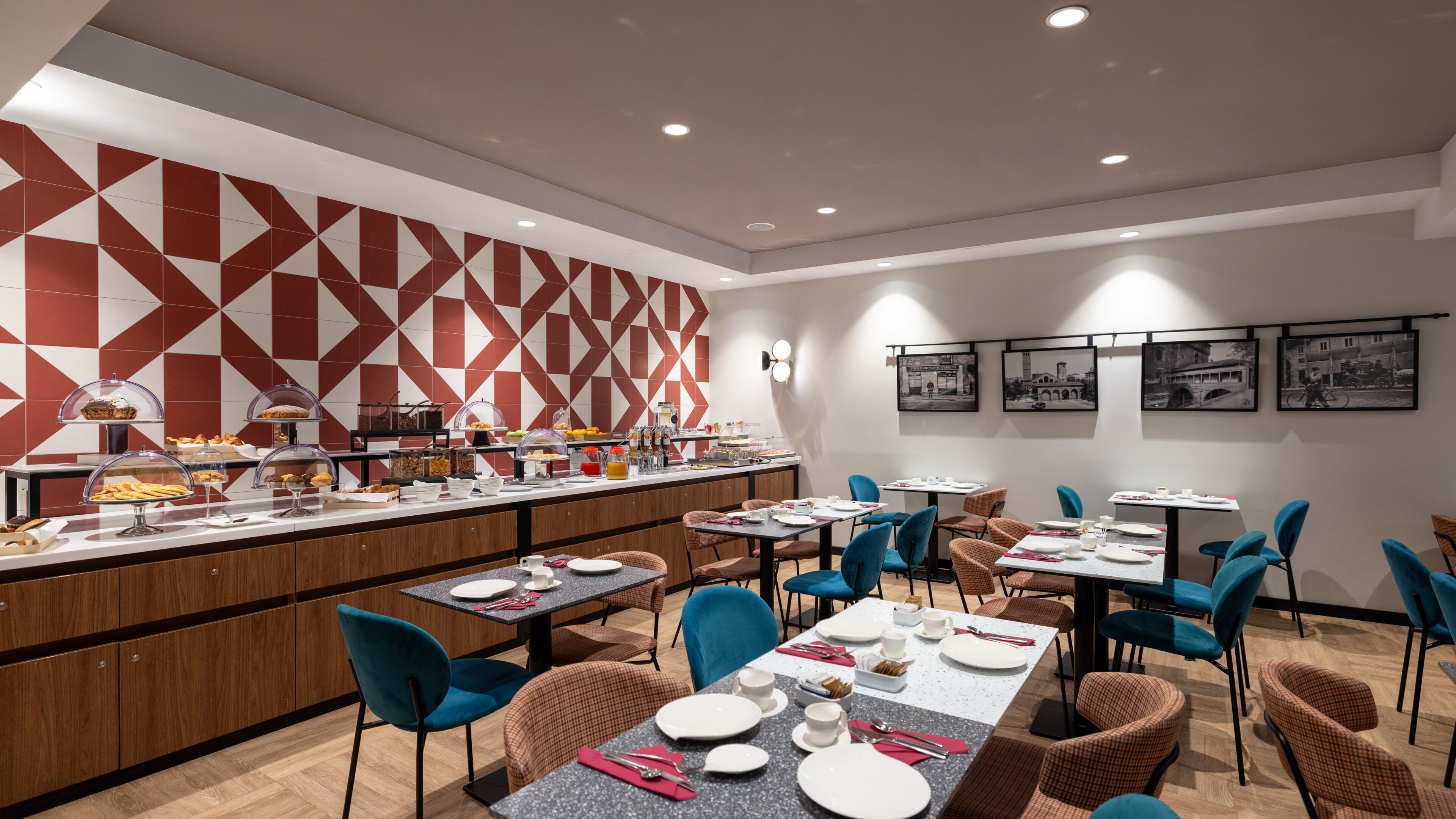 Ein moderner Essbereich mit Buffet, blauen und braunen Stühlen und einer Wand mit geometrischem Muster.